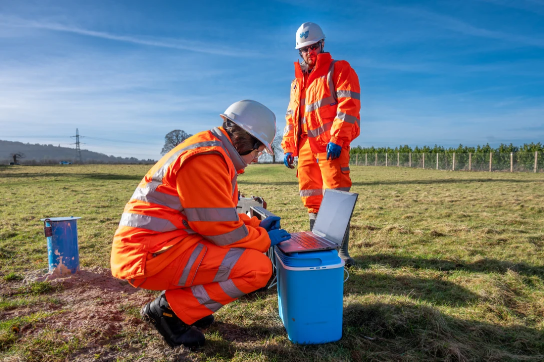 Workers in orange safety gear outdoors. surface water monitoring