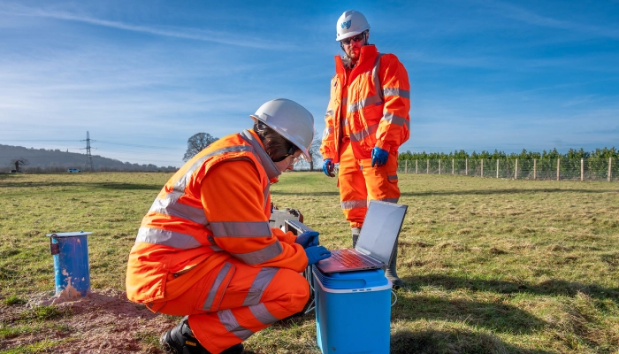 Two workers in safety gear outdoors.